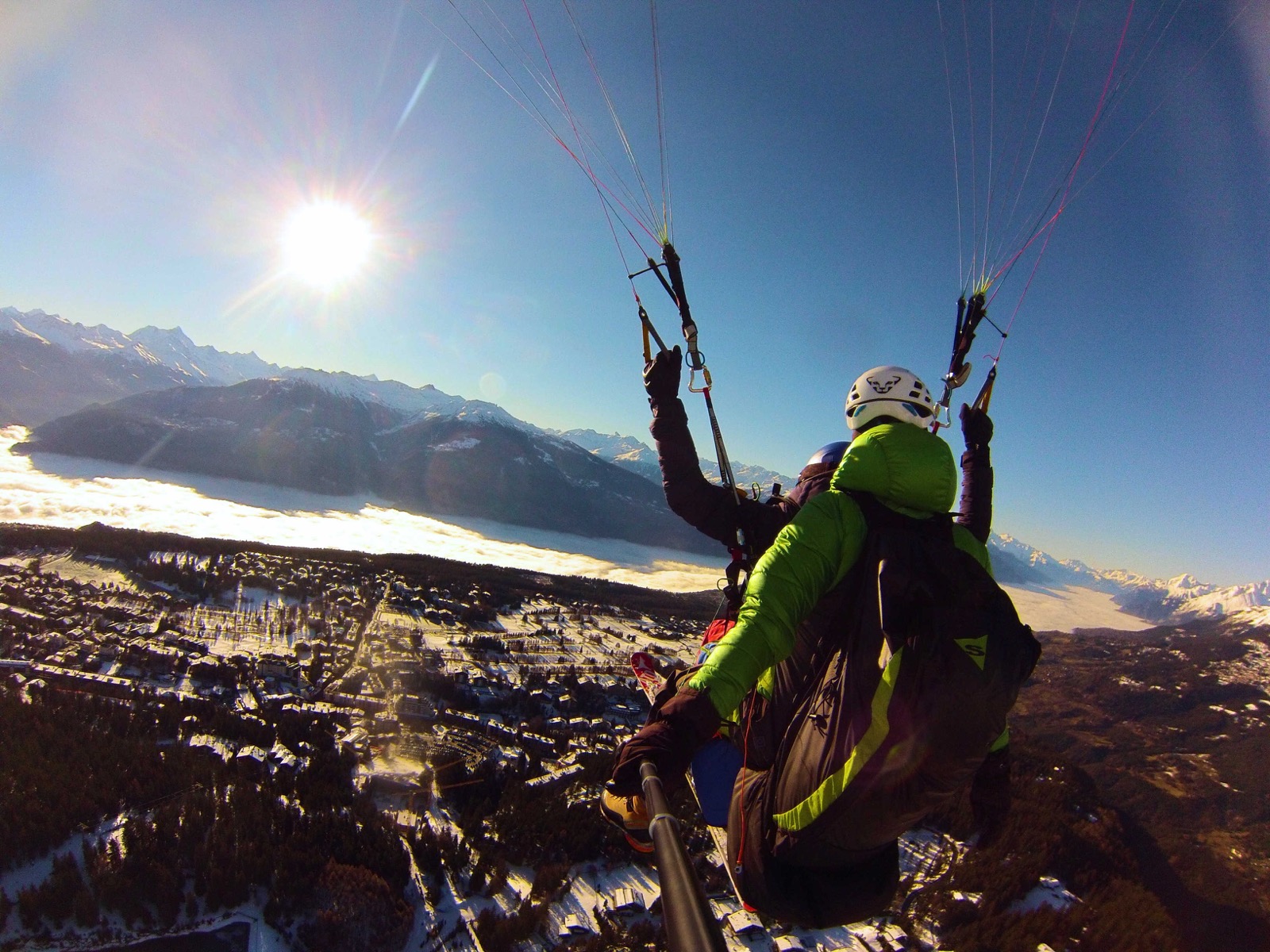 Pilote biplace en vol au soleil, au-dessus de Crans-Montana enneigé